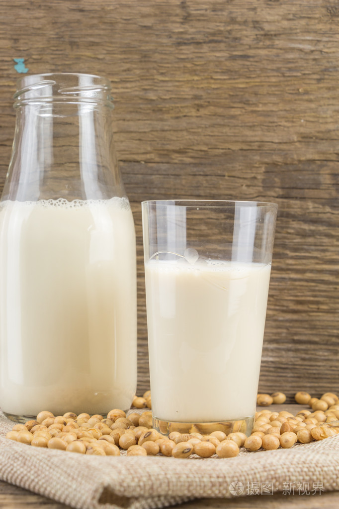 瓶子和杯子豆浆与大豆,在木制的背景上