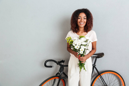 漂亮的微笑非洲女人与自行车和鲜花合影
