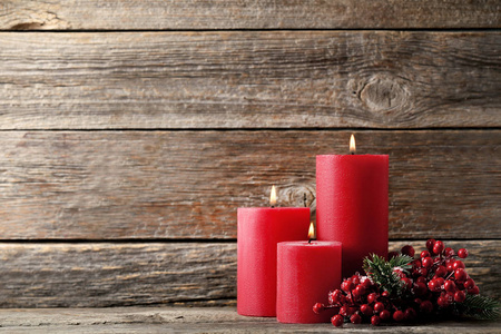 灰色木桌上的红色浆果圣诞蜡烛