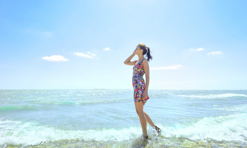 年轻女人站在海浪和抱着她的眼镜