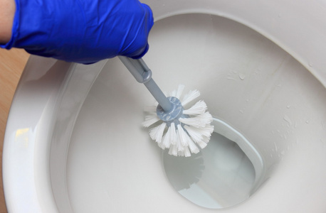 蓝色手套清洗马桶的女人的手照片