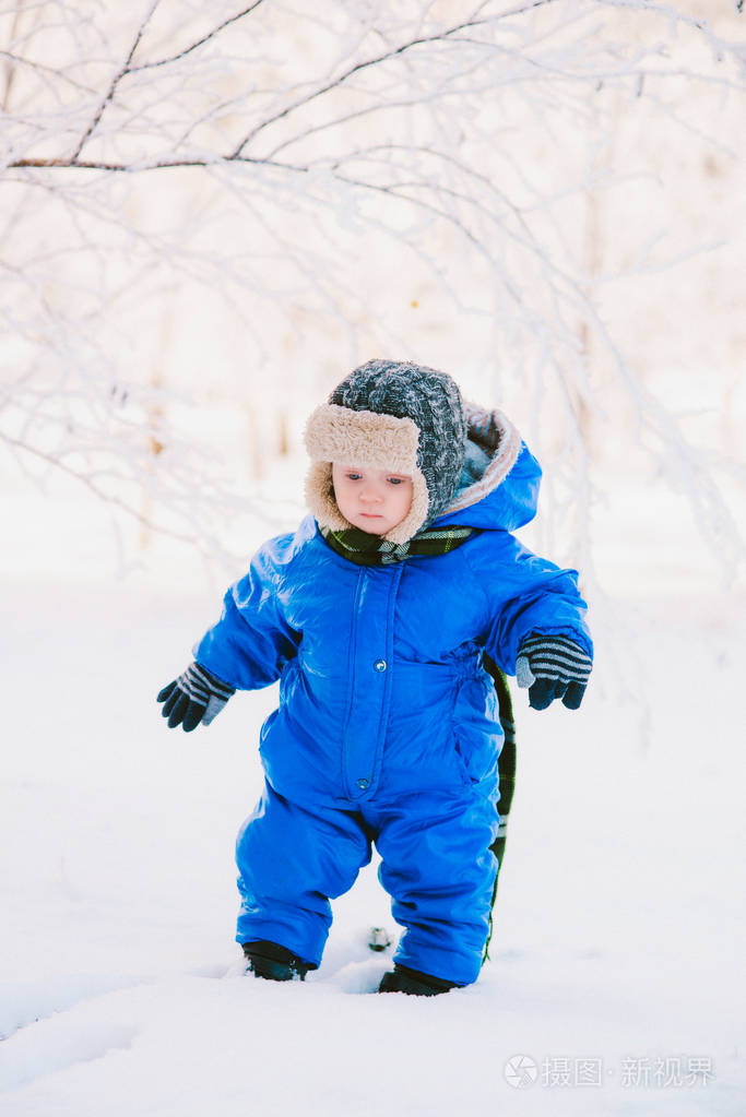一个穿着蓝色工作服的小男孩和一顶针织帽子, 在