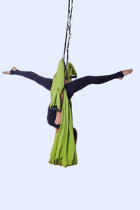在绿色吊床做空中瑜伽的少妇