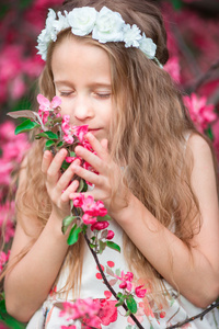 可爱的小女孩享受开花春天花园里的气味