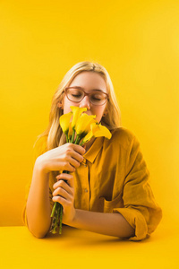女孩在黄色拿着美丽的黄色马蹄莲百合花
