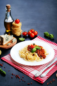意大利肉酱意大利面在白板上的白色和红色的餐巾。旁边制作面食的成分。意大利菜