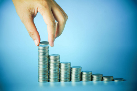 投资保存手把钱堆的硬币放在蓝色的背景,概念在增长,保存和商业投资