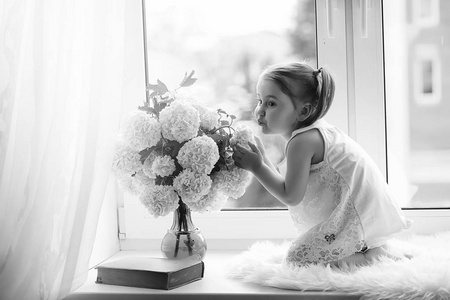 一个小女孩正坐在窗台上。一束鲜花