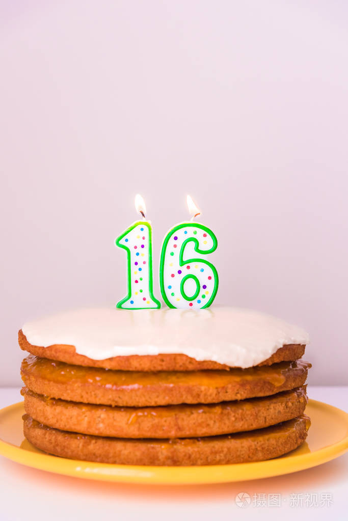 第十六生日蜡烛在质朴的纯素食层蛋糕粉彩背景
