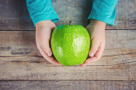 一个孩子手中的绿色苹果。选择性焦点