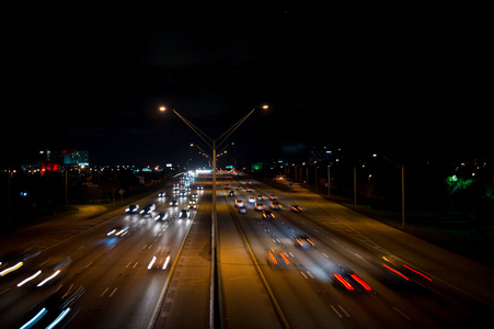 夜间在漆黑的天空中有汽车小径的公路道路