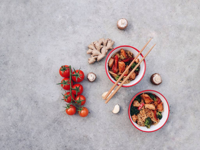 传统的亚洲锅面配鸡肉西红柿和筷子, 在五颜六色的碗上用混凝土石作背景。美味泰国晚餐