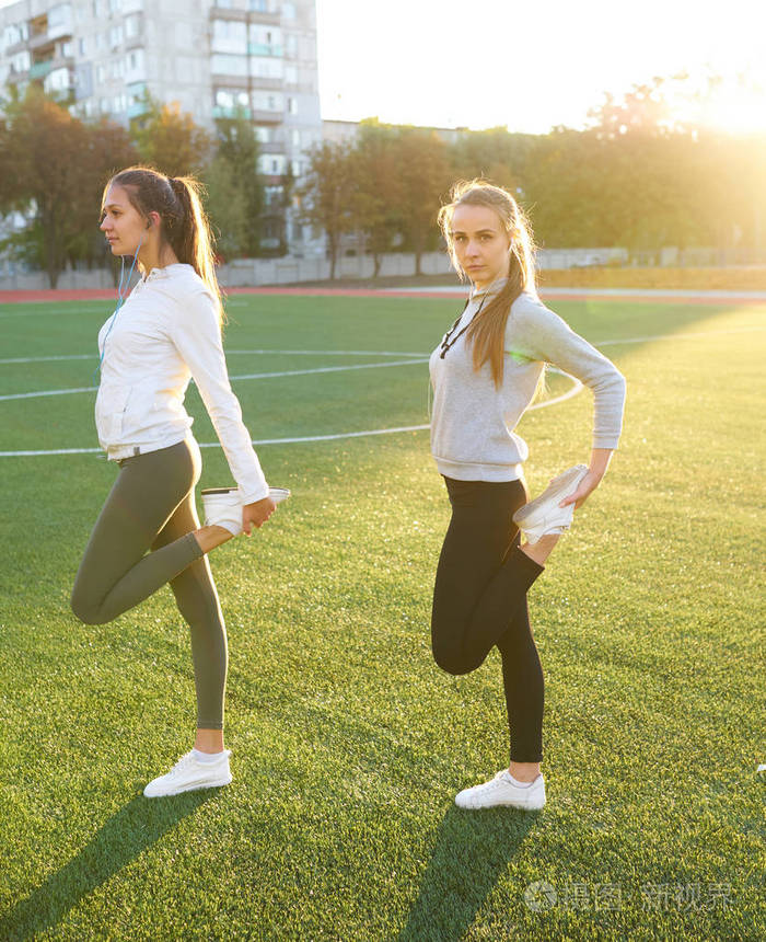 两个漂亮的运动女孩在清晨的草坪上一起锻炼