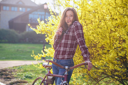 美丽的年轻女子，与在公园里的老式自行车