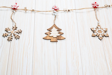 圣诞木制玩具以圣诞树和雪花的形式在一根白色的木制背景上的绳子上重。美丽喜庆贺卡与自由空间