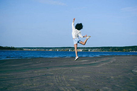 可爱的年轻女子卷曲的头发, 青春的浪漫, 一个旅程漫步在一个温暖的夏日阳光明媚的一天在沙滩上的水