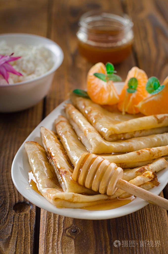 新鲜的薄饼与蜂蜜,枫糖浆,农舍乳酪和桔子.木制背景.顶部视图