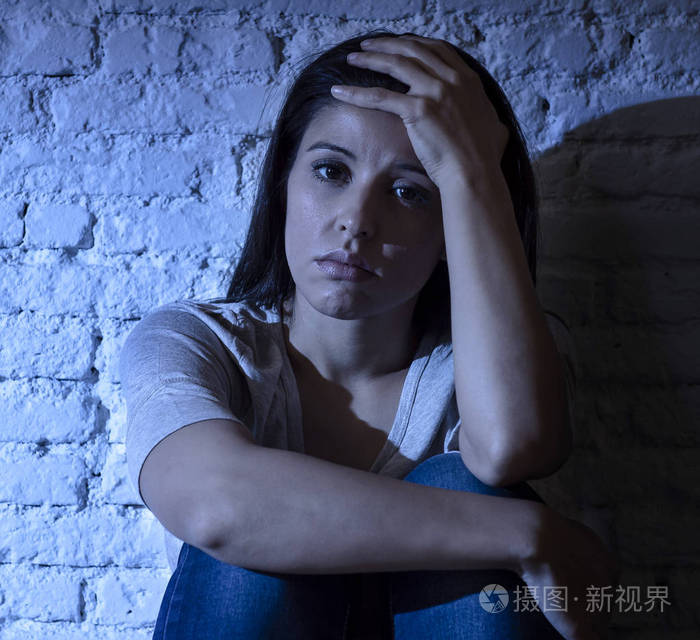 孤独的年轻迷人的拉美裔妇女坐在家里的地板沮丧的痛苦沮丧感到悲伤和