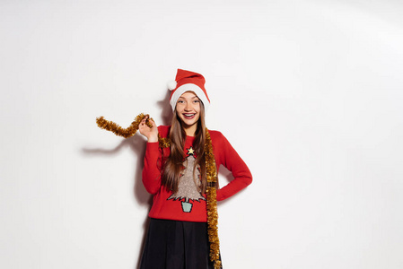 一个年轻漂亮的快乐女孩庆祝新年和圣诞节，戴着一顶红帽子和时髦的温暖的毛衣，在她脖子上的金缀