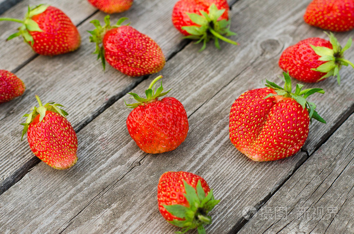 夏日浆果主题 : 成熟的红草莓一堆谎言在花园里,灰色木制的桌子上查看