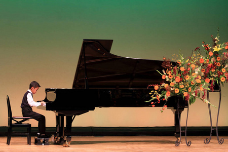 男孩一个人唯一的男孩日本男孩在台上弹钢琴(小学二年级)照片