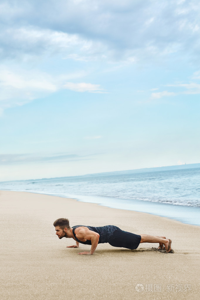 男人做推高锻炼在海滩上身体锻炼概念
