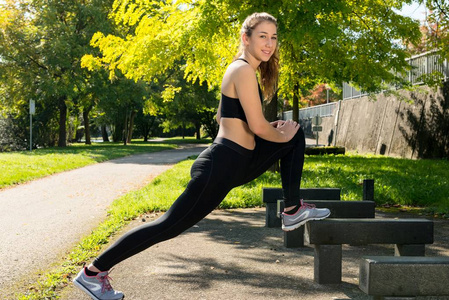 合适的女人，拉伸，在公园里锻炼的侧视图