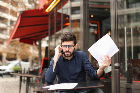 生意人争论由智能手机和阅读文件在咖啡馆标签