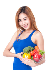 年轻女子捧着篮子的蔬菜。健康概念