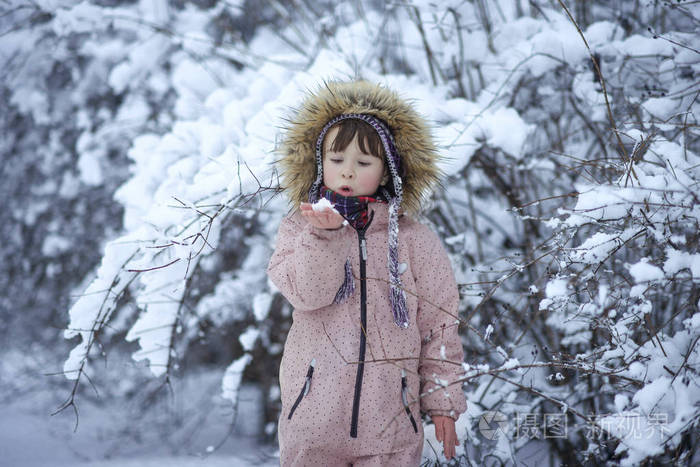 女孩在公园里拿着雪花在她的手中