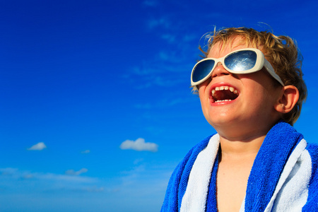 小男孩笑裹在沙滩巾上天空照片