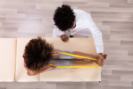 理疗师协助女性患者在临床上进行黄丝带运动照片