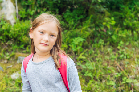 一个可爱的小女孩在森林里徒步旅行的肖像。