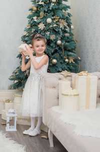 可爱的小女孩穿着白色礼服在圣诞前夜拿着礼物