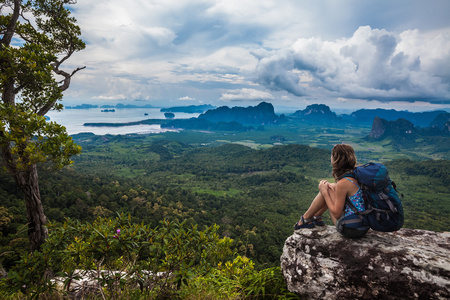 年轻的背包客坐在悬崖上照片