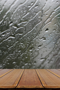 雨水落在玻璃窗口背景与木材表