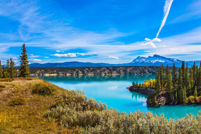 在蓝天上的银色痕迹的飞机.宏伟的绿松石亚伯拉罕湖.生态旅游的概念