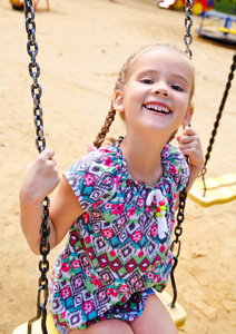 微笑在公园的秋千上玩的小女孩