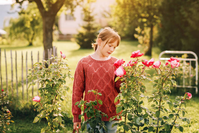 小女孩在美丽的玫瑰园里玩耍