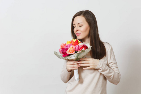 年轻的微笑的女人嗅着和捧着花束的美丽玫瑰花在白色背景上隔绝。广告的复制空间。St. 情人节或国际妇女节概念