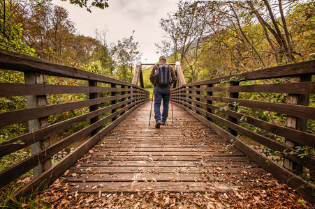 成熟的男人是山中徒步旅行，在一座木桥上行走