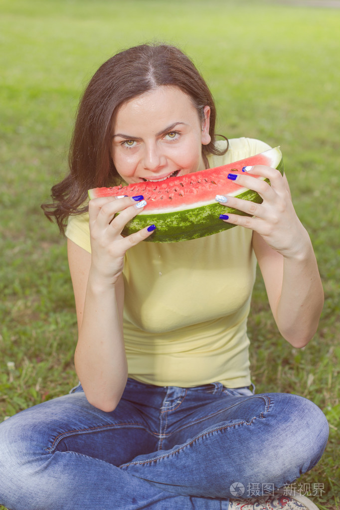 微笑着的年轻女人吃西瓜