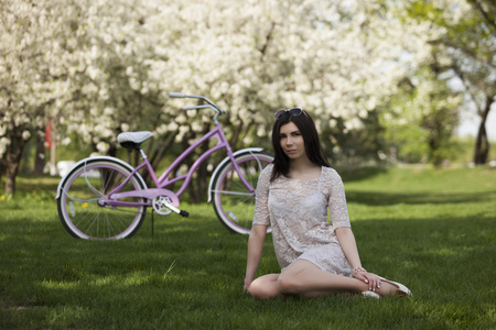 年轻的女孩，在裙在公园骑自行车