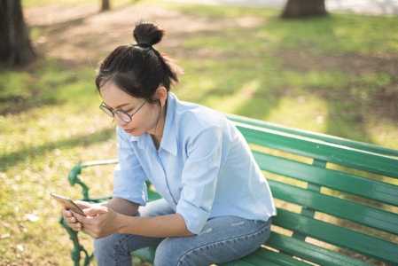 花园坐在长凳上的亚裔女子