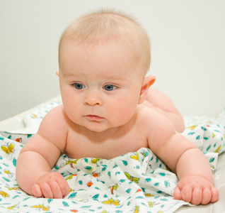 大灰蓝色的眼睛，躺在一条毯子，灰色的背景上周到婴幼儿