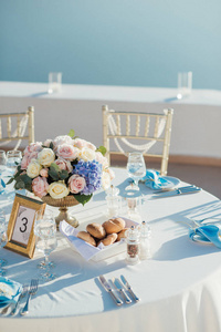圣托里尼岛上的餐桌上的婚礼装饰, 金色, 蓝色和白色的玫瑰花束和金色的框架