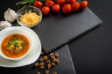 陶瓷杯番茄凉菜汤与绿色的酱汁, 盐和罗勒的旧黑色铁背景与复制空间。健康饮食理念