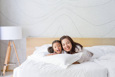 快乐的亚洲家庭母亲和女儿在床上微笑