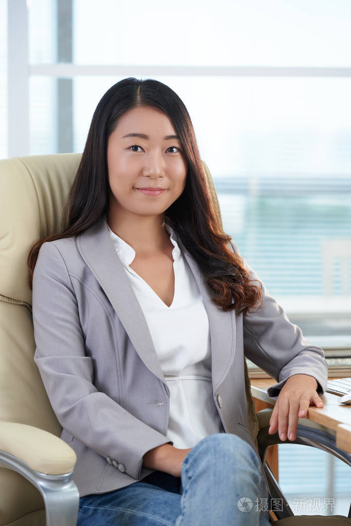 微笑的年轻自信的商界女性坐在办公室照片-正版商用图片0eoybb-摄图新