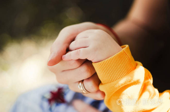 婴儿握住他妈妈的手支持和关心母亲